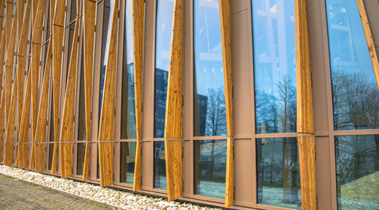 Outside of a wooden building with windows, trees and buildings in the reflection